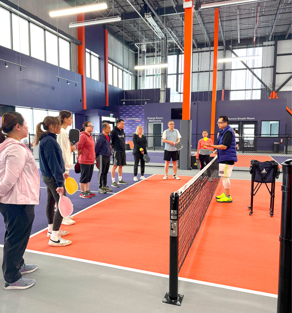 beginners on court, coach with small group, bright room.