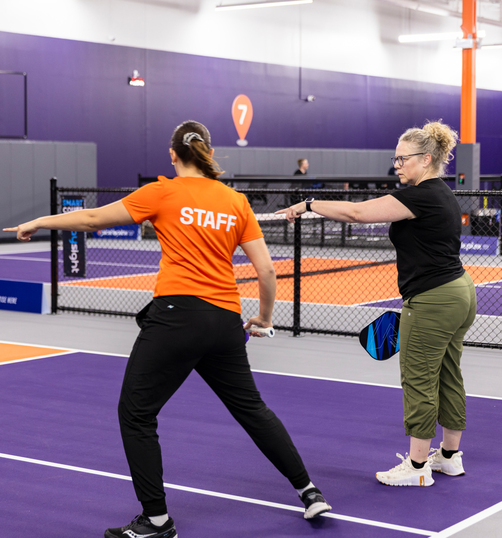 beginners on court, coach with small group, bright room.
