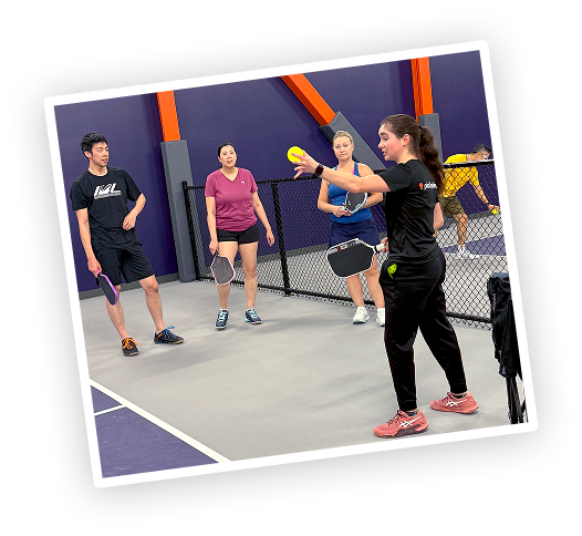 beginners on court, coach with small group, bright room.